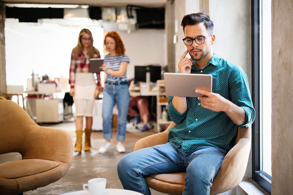 Visão aérea de duas pessoas apertando as mãos sobre uma mesa de escritório organizada, selando um acordo com relatórios e um tablet ao lado.